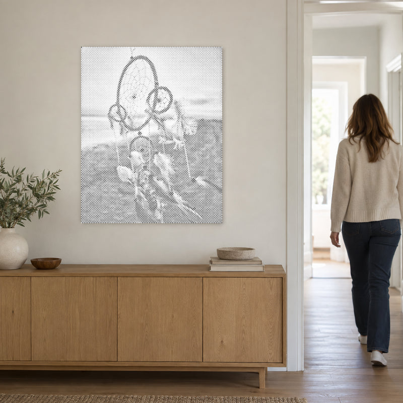 Stippenschilderij “Dromenvanger in de Wind”, aan een lichte muur, met iemand die door de deur ernaast loopt.