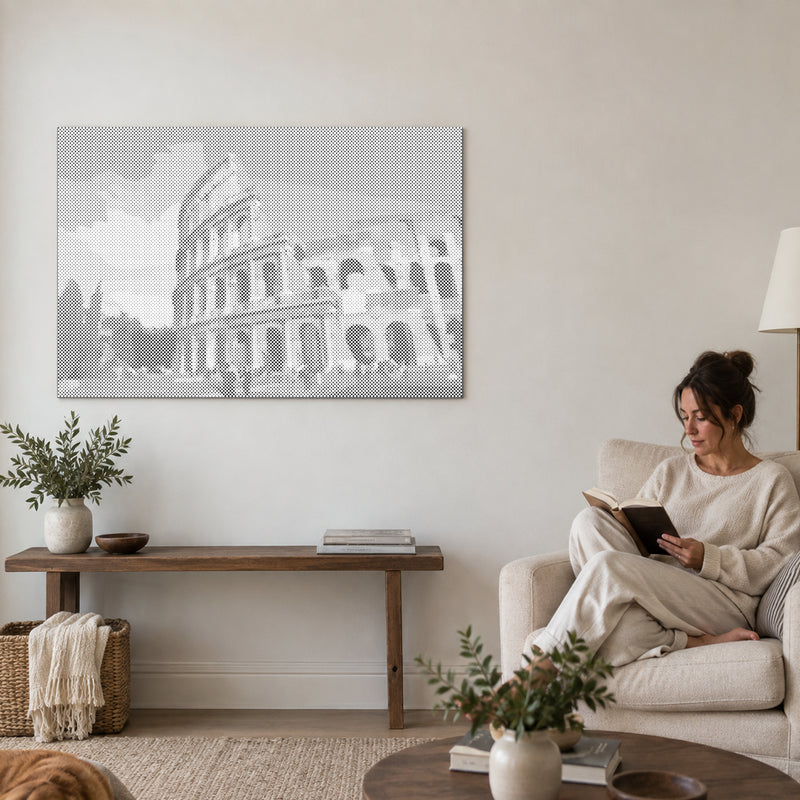Stippenschilderij “Colosseum Rome”, aan een muur in de woonkamer, met iemand die ernaast in een fauteuil leest.