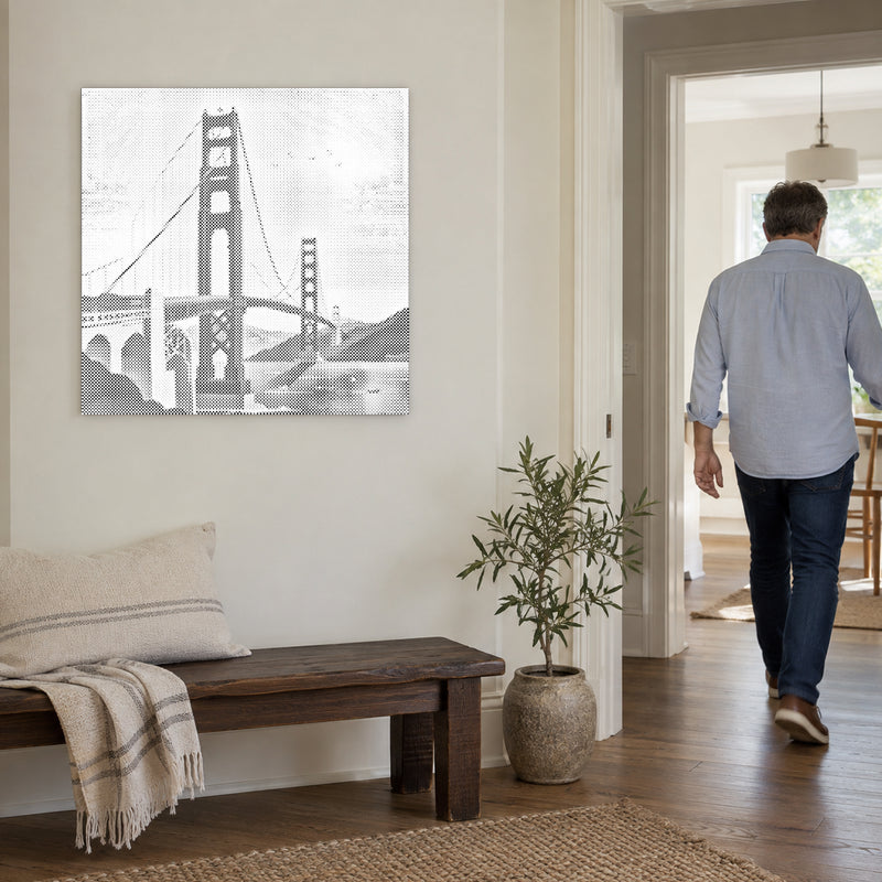 Stippenschilderij “Golden Gate Bridge”, aan een lichte muur, met iemand die door de deur ernaast loopt.