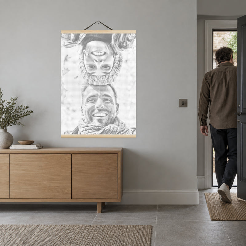 Magnetische lijst voor stippelschilderijen, aan een lichtgrijze muur in de hal, met iemand in de deuropening.
